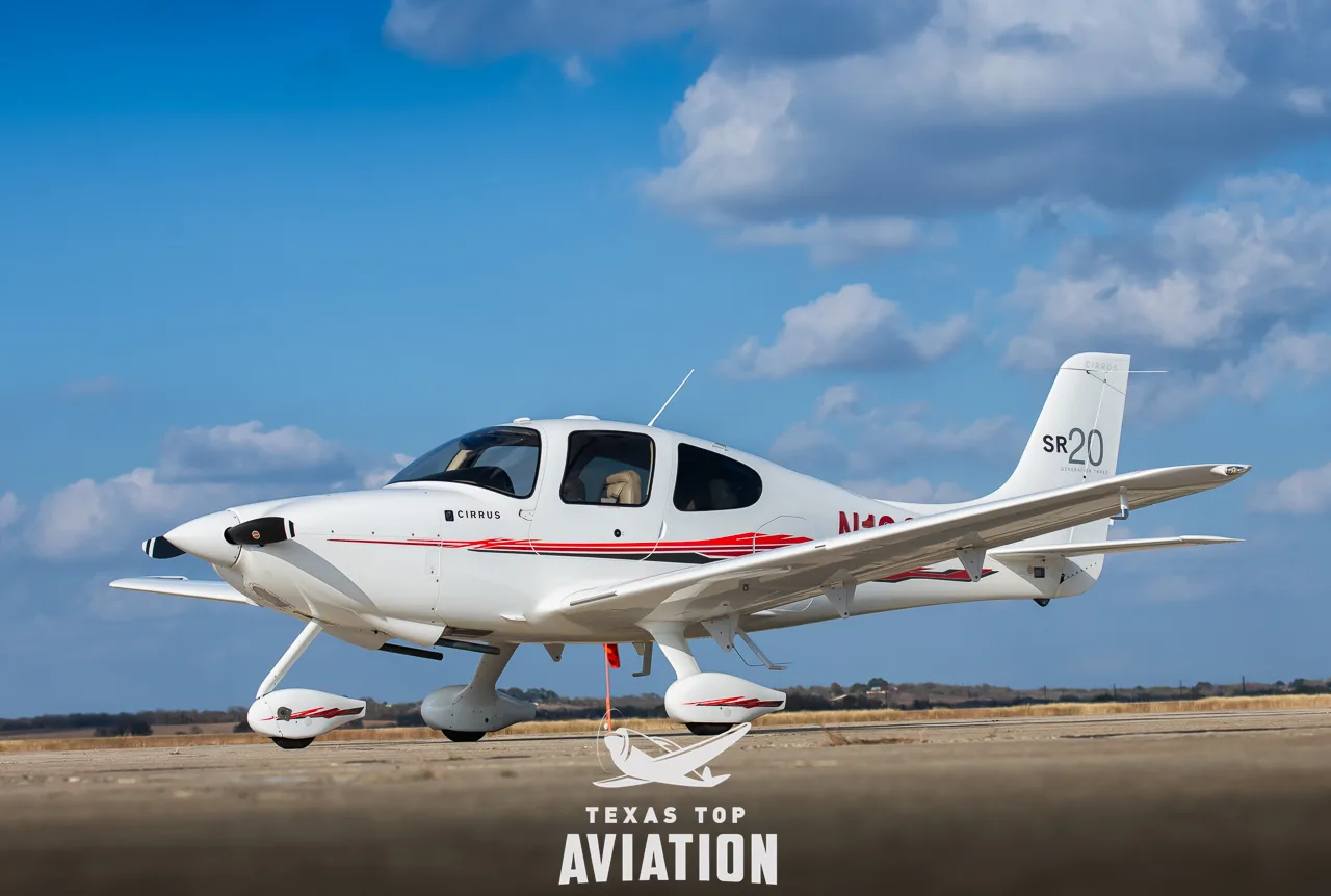 A white Cirrus SR20 is parked on the tarmac.