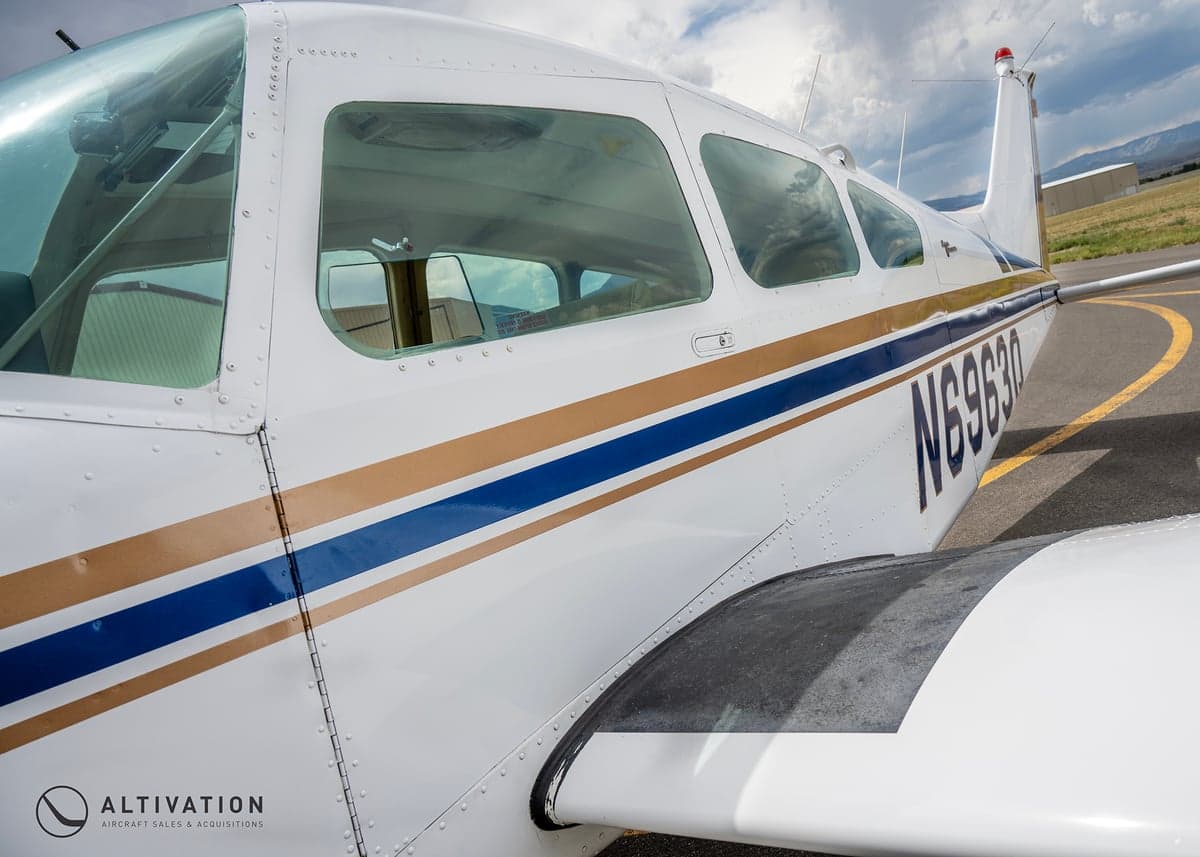 Close up of the side of a white and blue Piper aircraft showing the registration number.