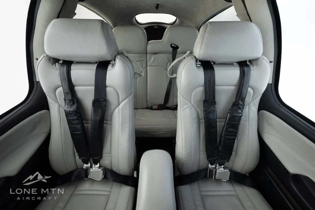 A view from the rear of the light gray leather seats in the Cirrus SR20 aircraft cabin.