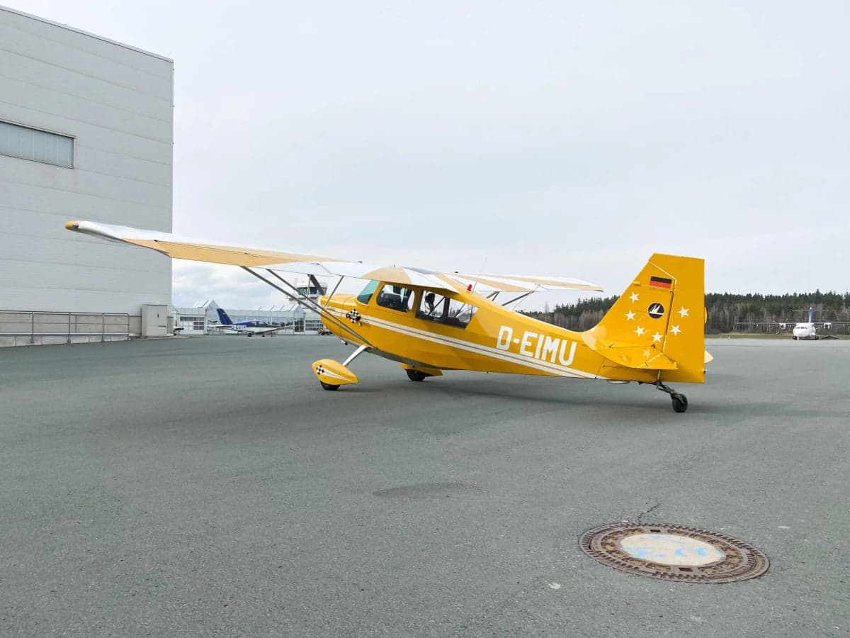 Rear view of a yellow and white aircraft, D-EIMU, parked on the tarmac.