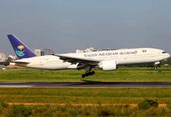 A Saudi Arabian Airlines Boeing 777 landing on a runway.