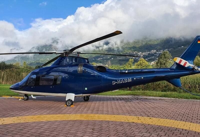 A blue AgustaWestland AW109SP helicopter, registration D-HABM, is parked on a helipad.