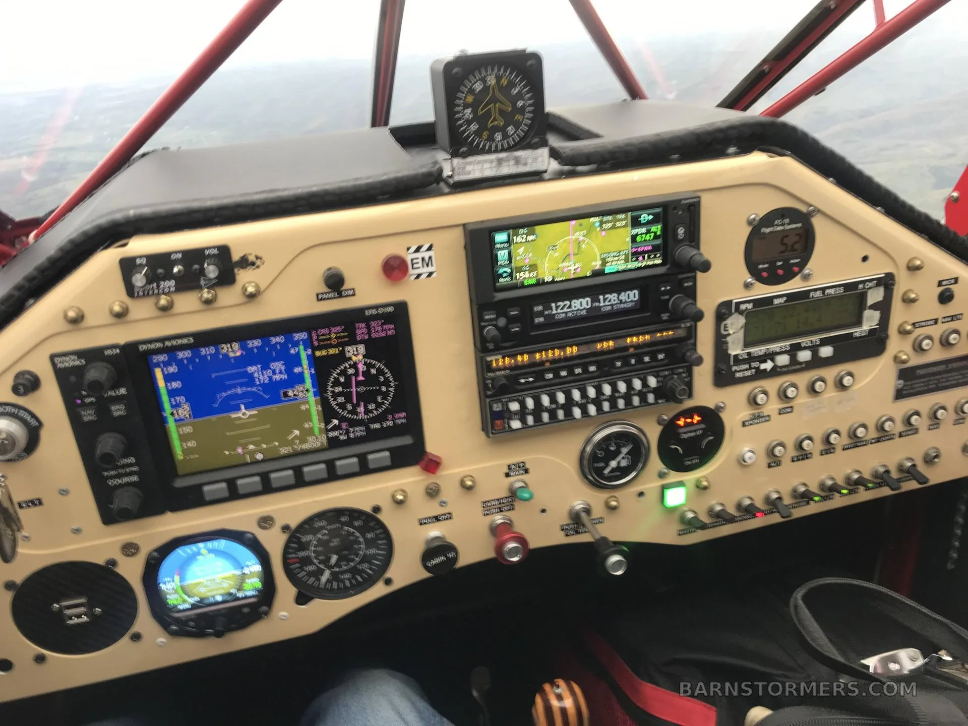 The cockpit of an aircraft showing multiple digital displays, analog gauges, and control switches.