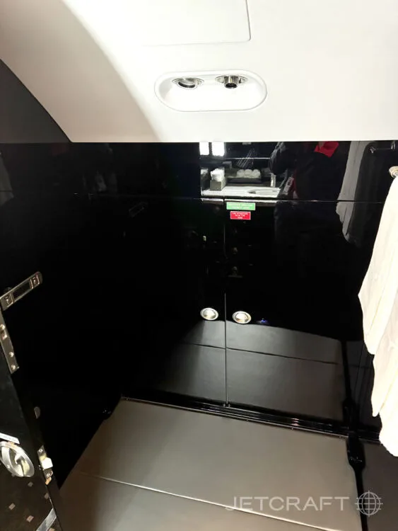 A small interior compartment of the private jet, featuring dark glossy walls and a light-colored floor.