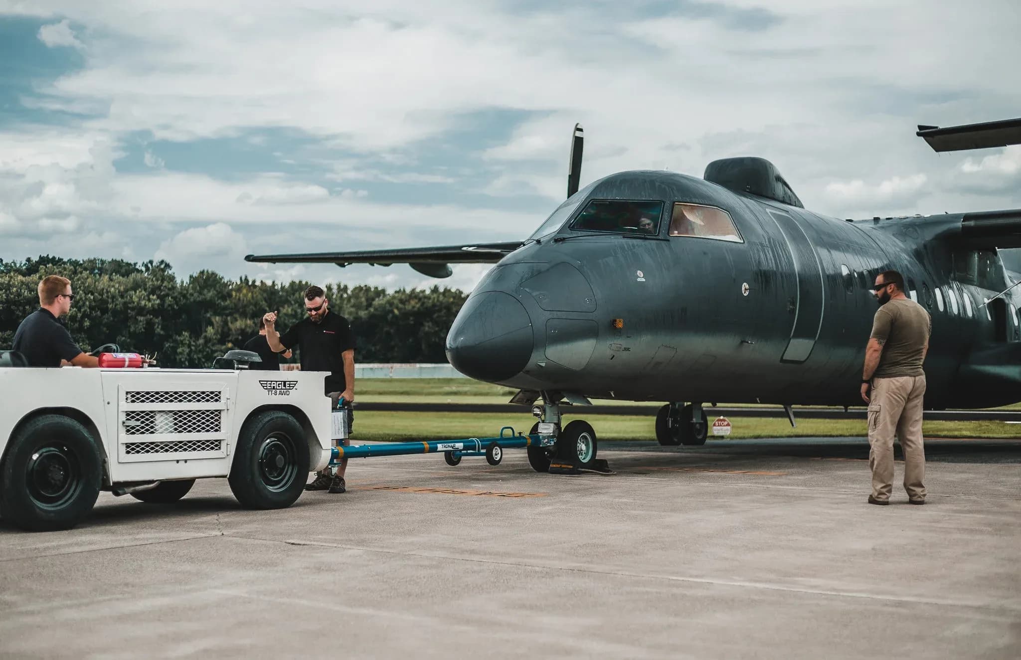 A dark gray turboprop aircraft being towed on the tarmac.