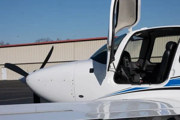 Close up of the cockpit and wing of a white Cirrus aircraft.