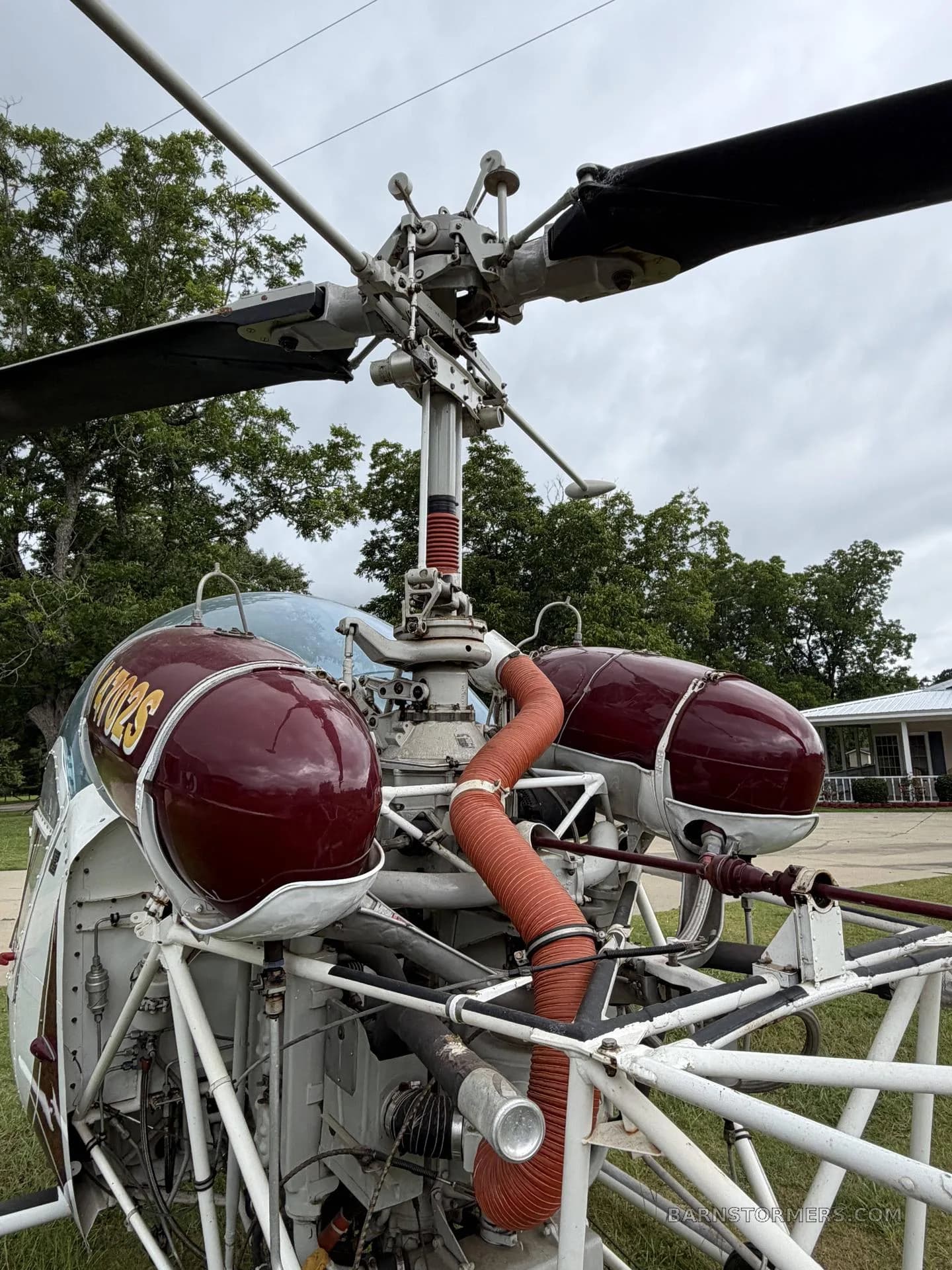 A close-up view of the main rotor mast and engine components of the red and white helicopter.