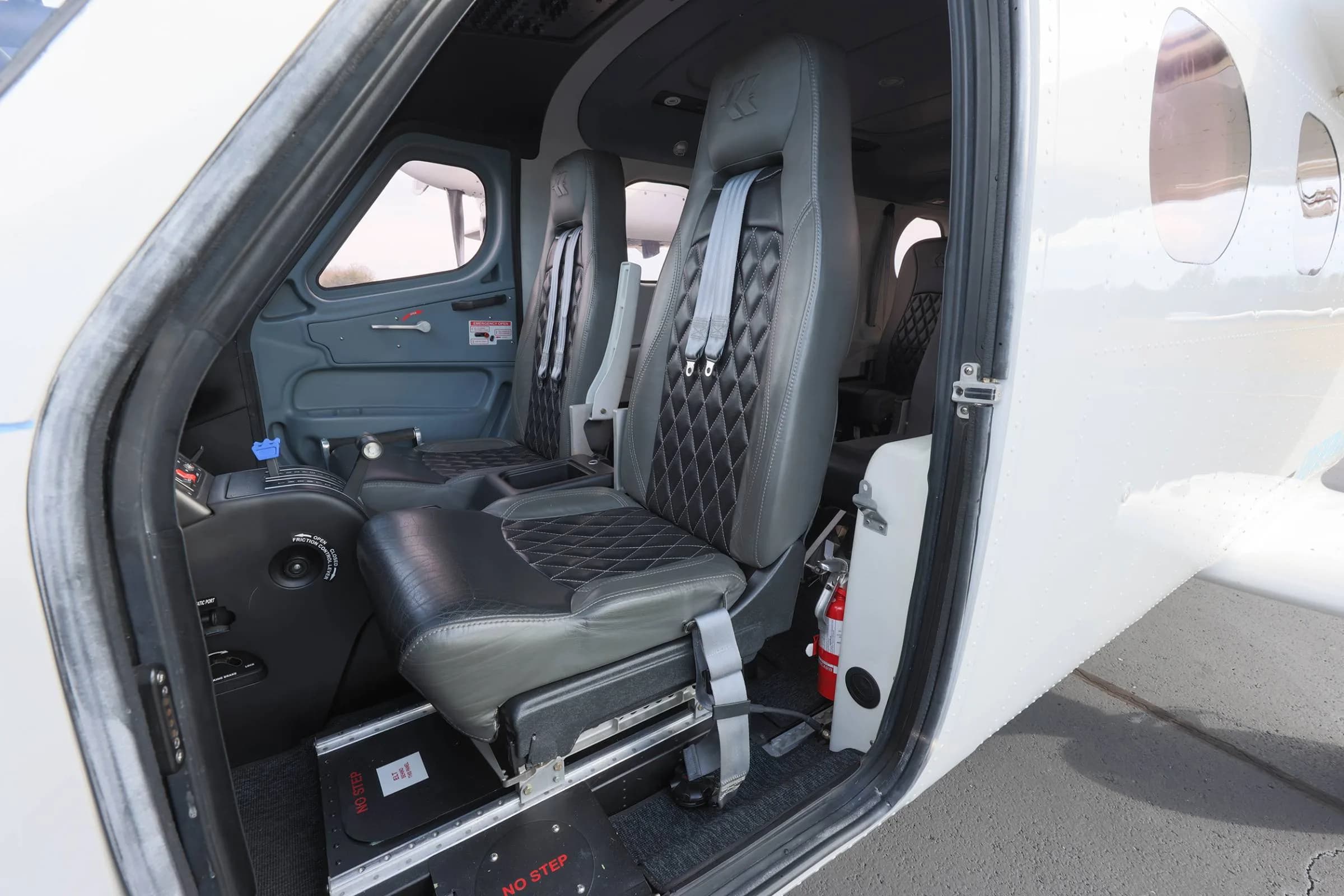 View of the aircraft cabin with gray seats and open door.