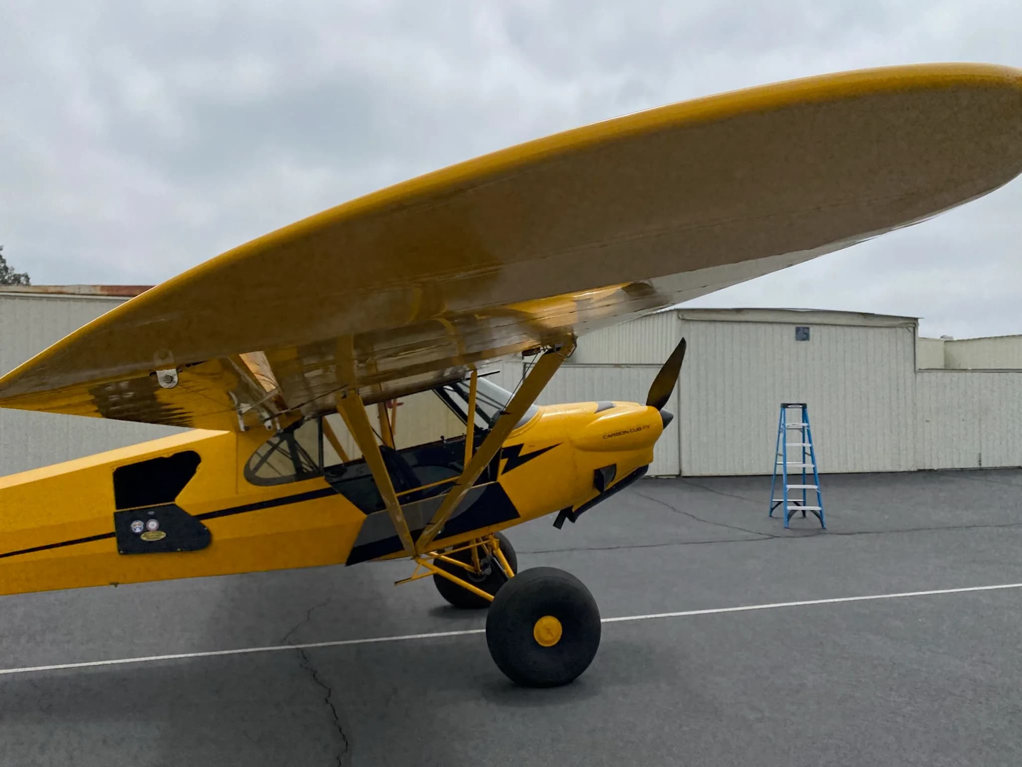 Side view of a yellow Carbon Cub aircraft on the tarmac.