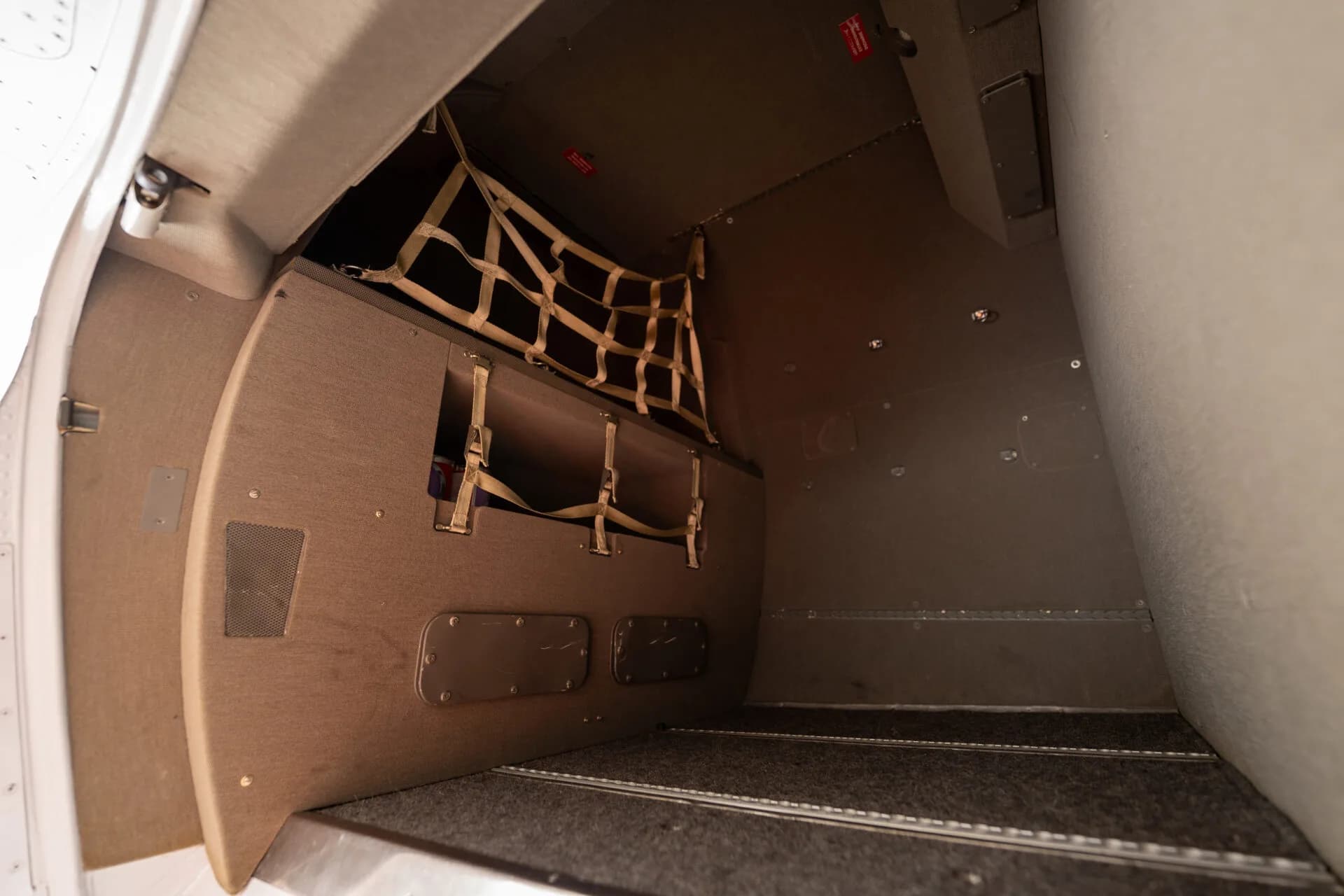 The interior of an aircraft's cargo compartment with a net for securing items.
