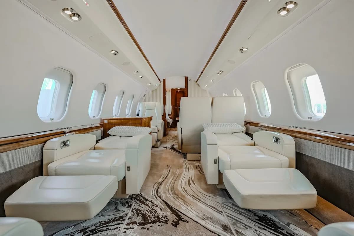 A luxurious aircraft cabin interior with light-colored lounge seats and a patterned carpet.