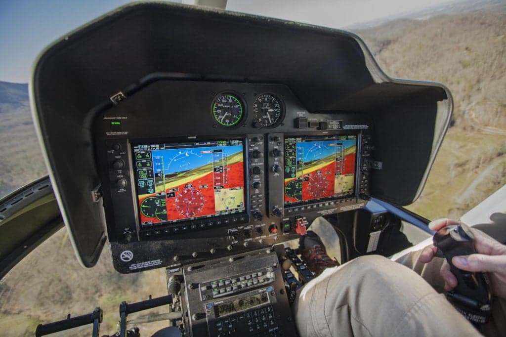 View of the helicopter cockpit with dual display screens and controls.