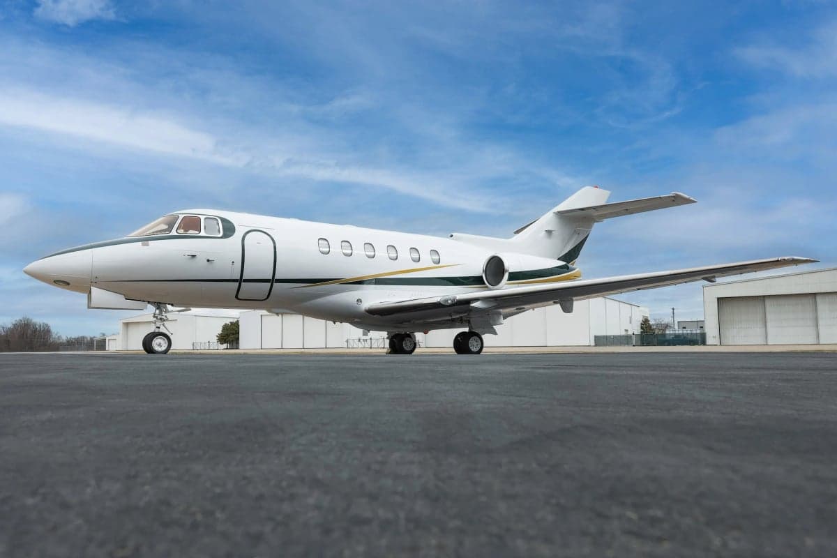 Hawker 800XP on the tarmac with a white and gold paint scheme.