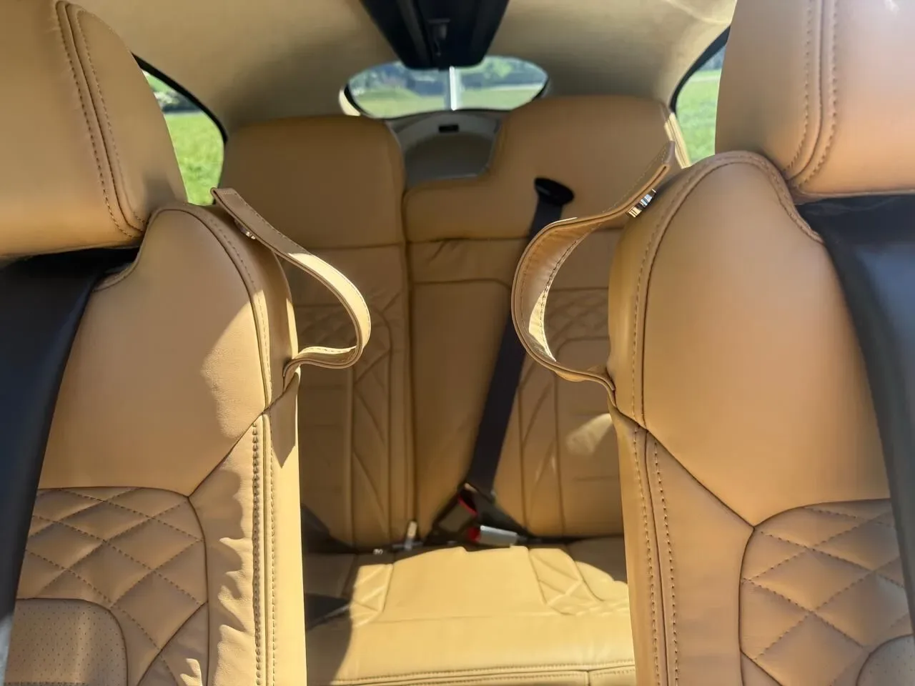A close-up view of the tan leather rear seats with diamond stitching in a Cirrus SR22 aircraft.