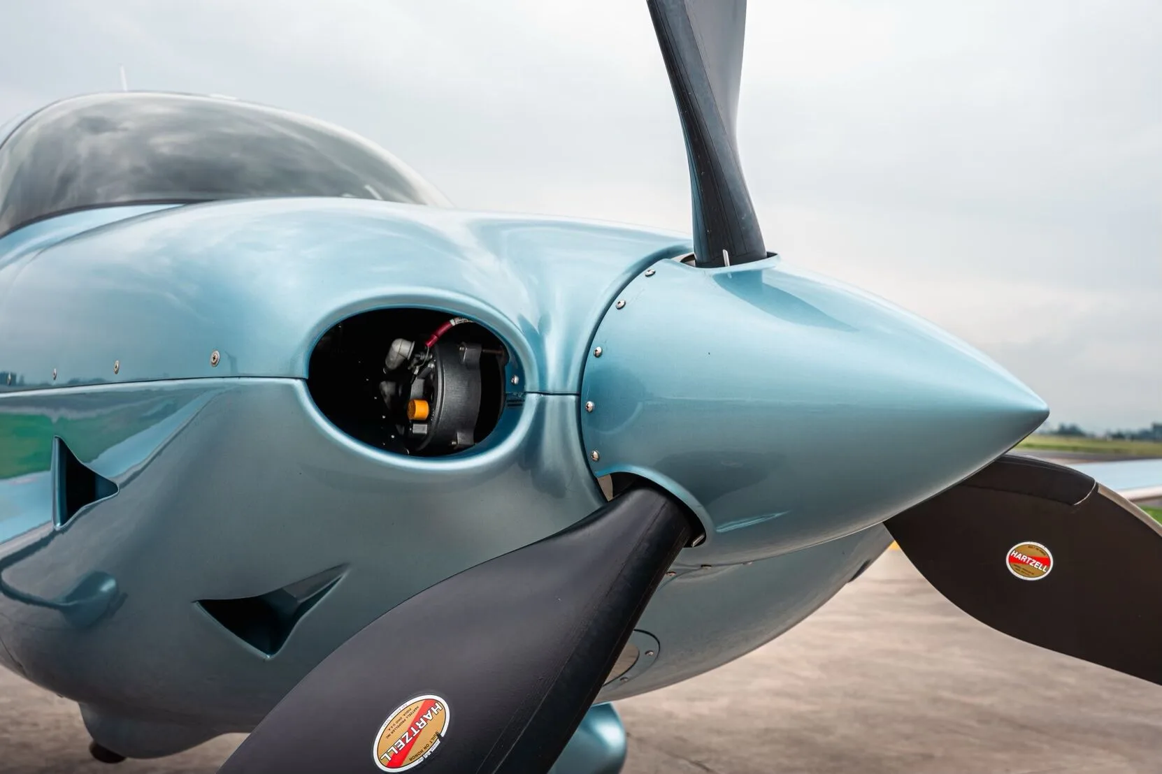 Close-up view of the propeller and nose of the light blue Cirrus SR22T aircraft, showing a landing light.