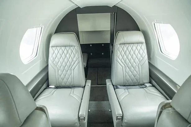 A close-up view of the aircraft's interior cabin with two light grey quilted leather seats.