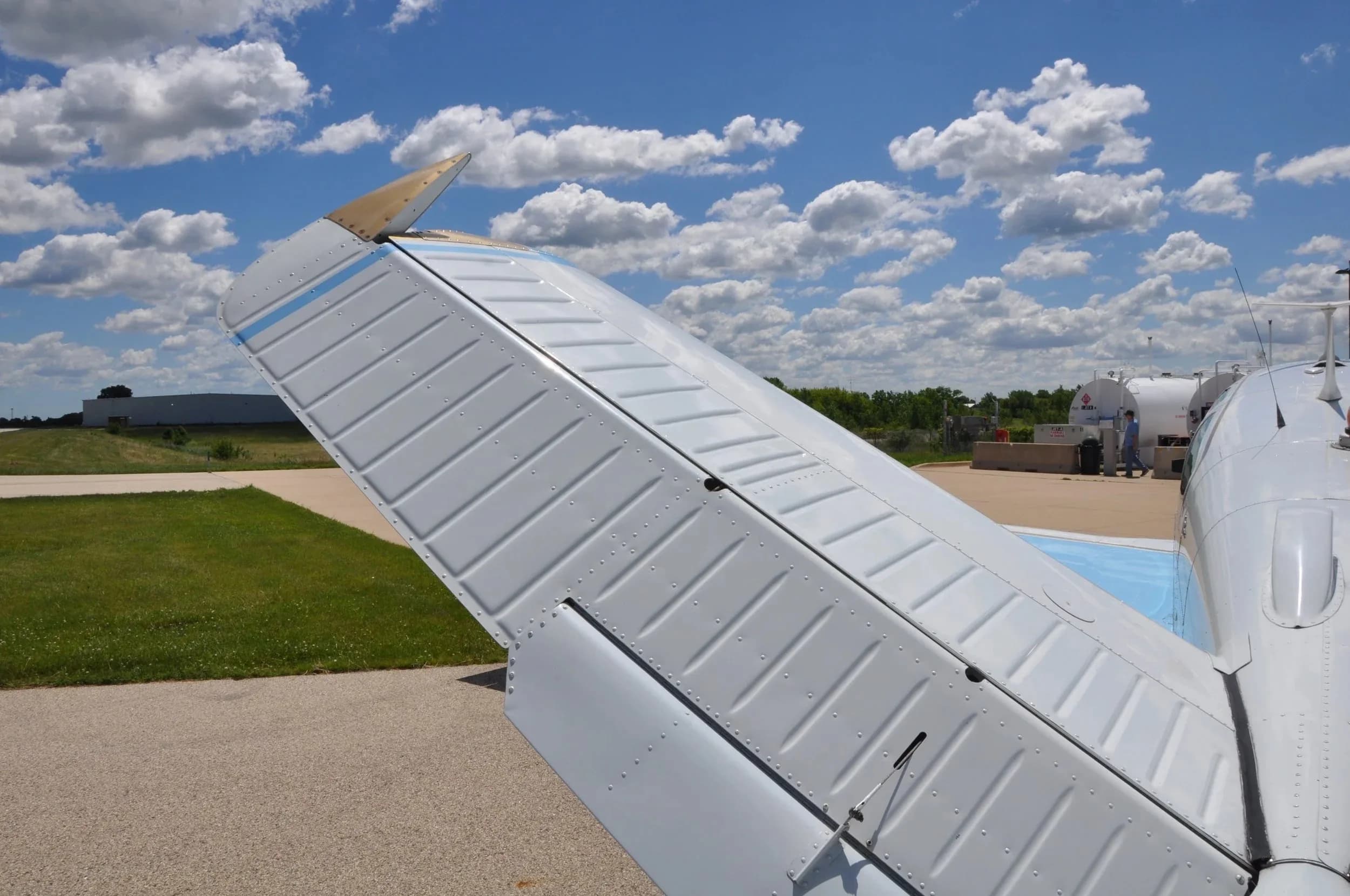 An overhead close-up view of the right horizontal stabilizer of the light blue and white Beechcraft Bonanza.