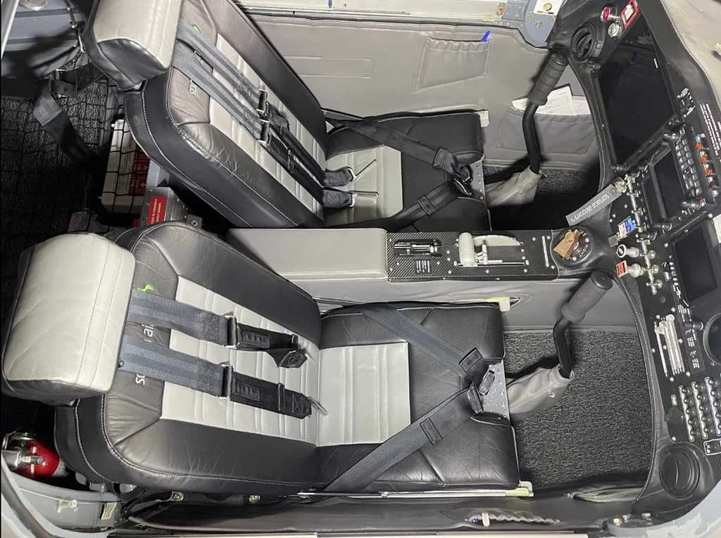 View of the two-tone black and grey leather seats and center console of the aircraft's cabin.
