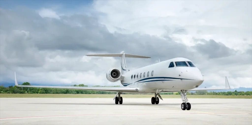 Gulfstream G650ER aircraft on the tarmac with a cloudy sky overhead.