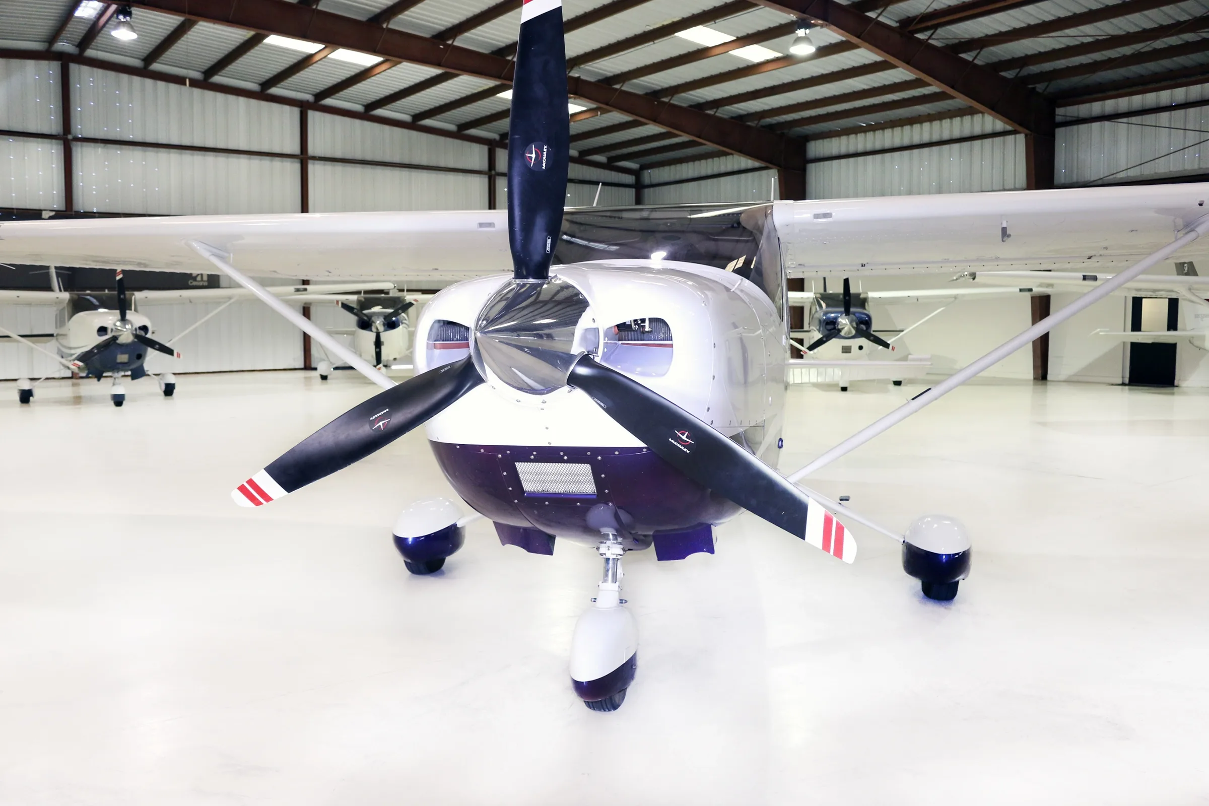 A head-on view of a white and blue Cessna Skylane aircraft with registration N401SW in a hangar.