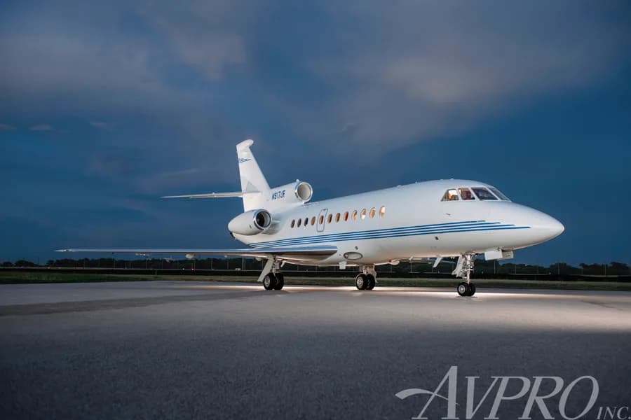 A Dassault Falcon 900EX, tail number N917JF, parked on a tarmac at night with blue skies.