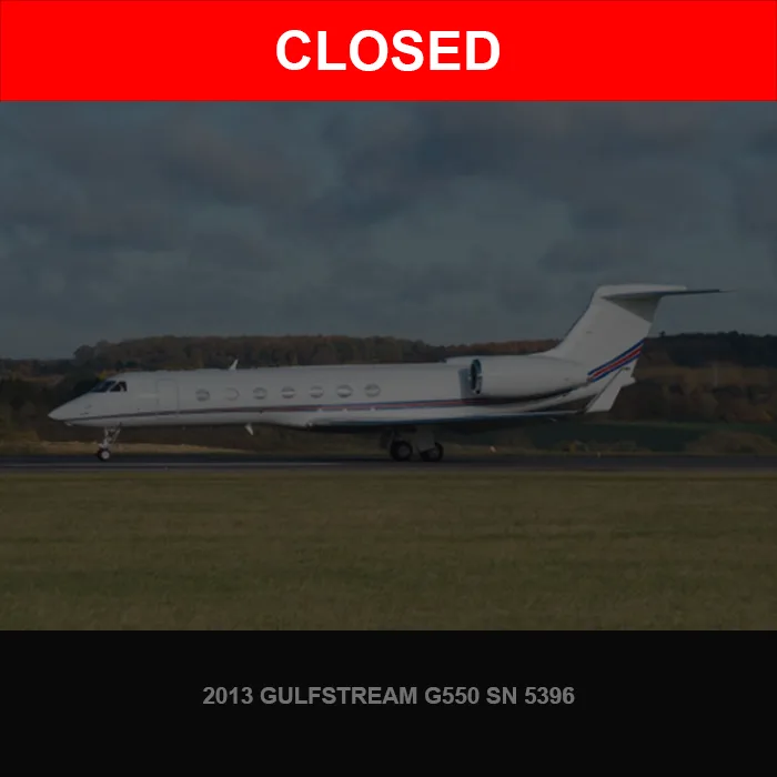 A white Gulfstream G550 business jet with blue and red stripes on the tail and fuselage is seen from the side on a grassy airfield under a cloudy sky.