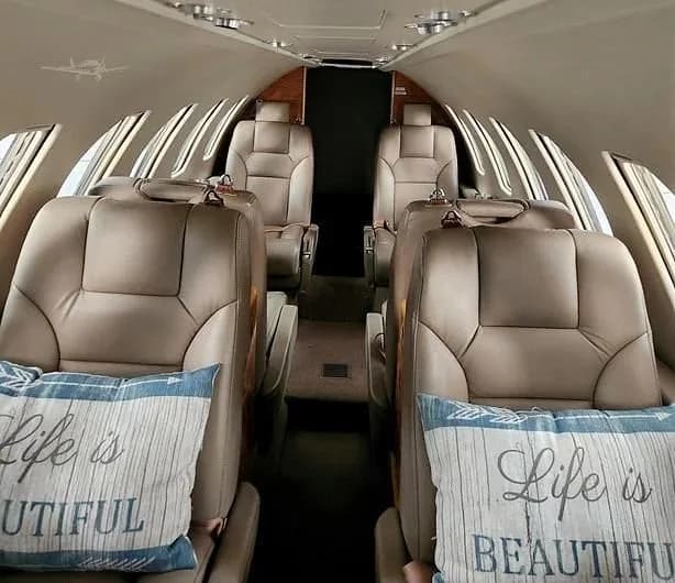 The aircraft's cabin interior features tan leather seats and decorative pillows.