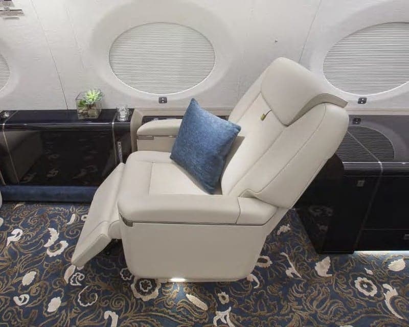 Aircraft interior with a reclined seat and blue pillow.