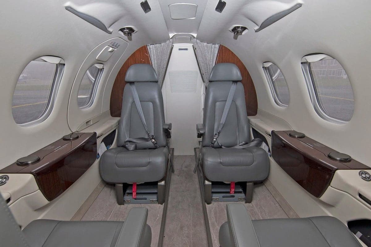 View of the aircraft interior showing forward-facing seats and side tables.