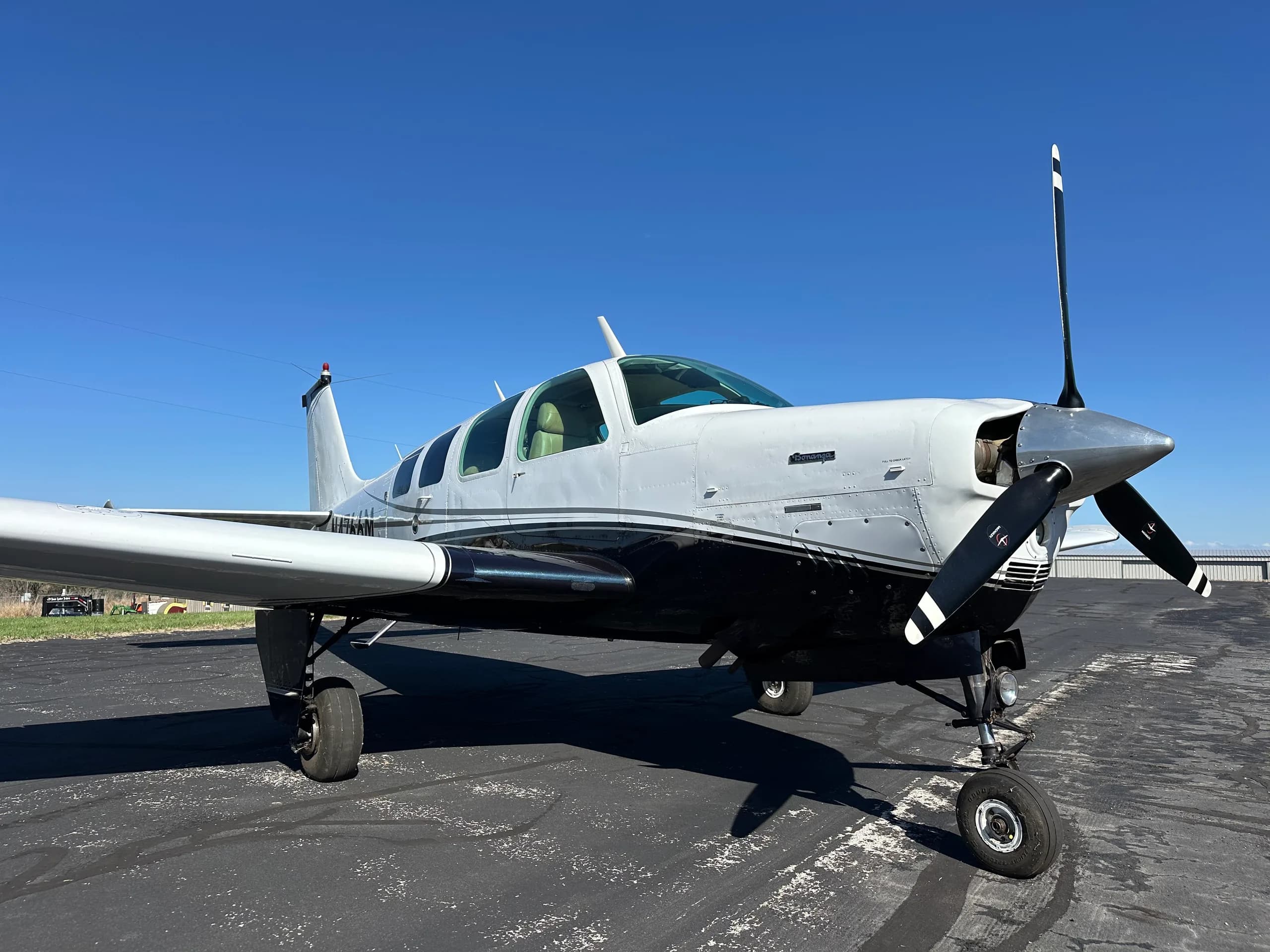 A close-up of the front of a Beechcraft Bonanza aircraft with a white and black paint scheme.