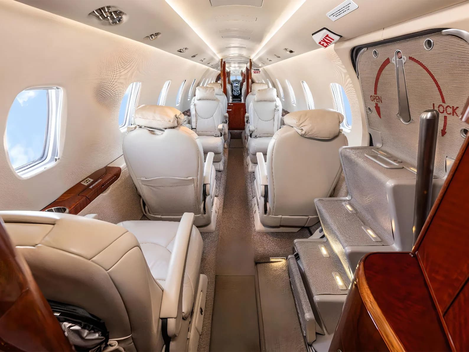 The private jet cabin interior viewed from the entry door, showing light leather seats and a lighted stairwell.
