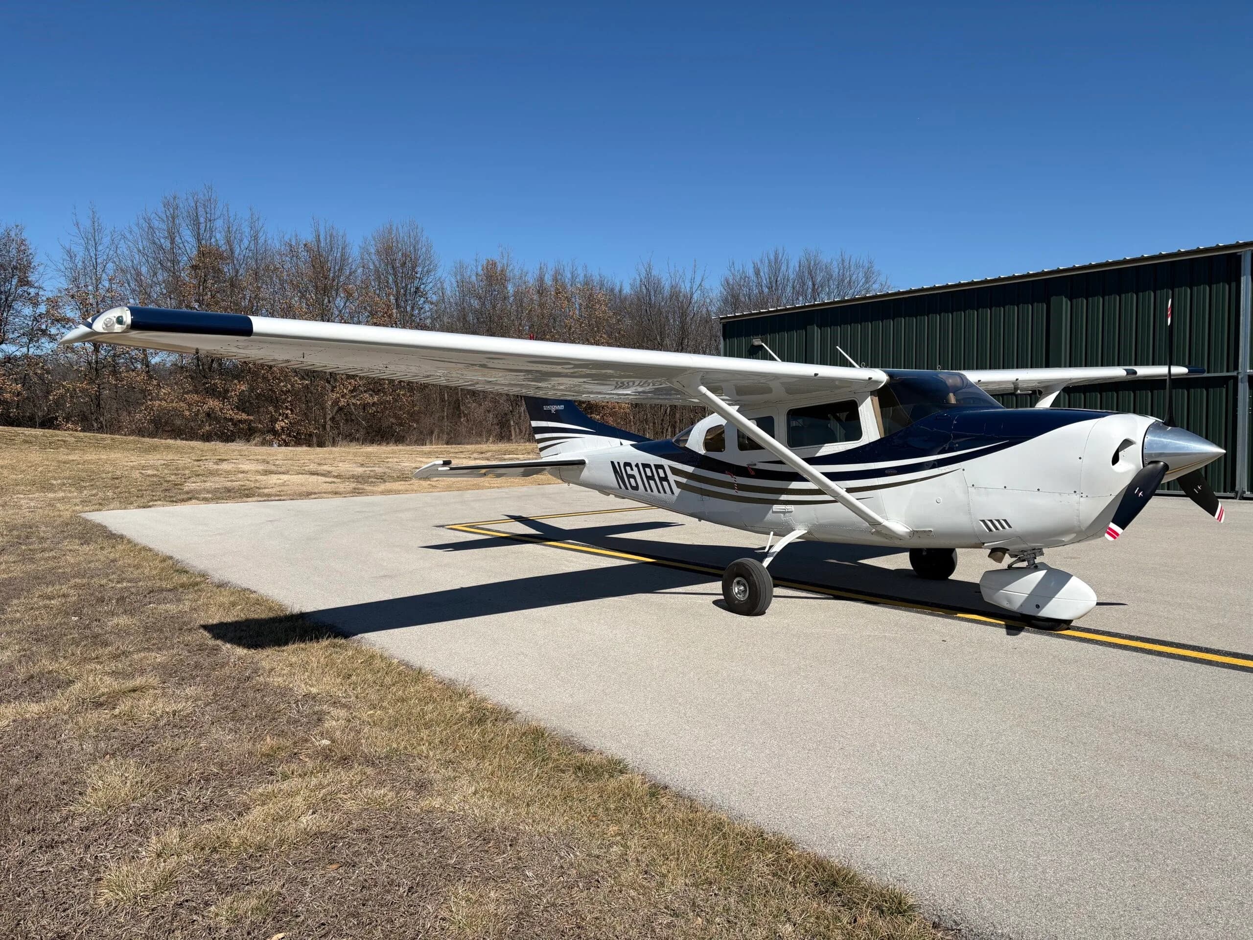 Side view of a white and dark blue Cessna Stationair TC aircraft with registration N61RR parked on an airfield.