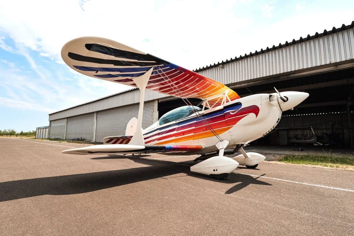 Christen Eagle II biplane with colorful paint scheme parked on the tarmac.