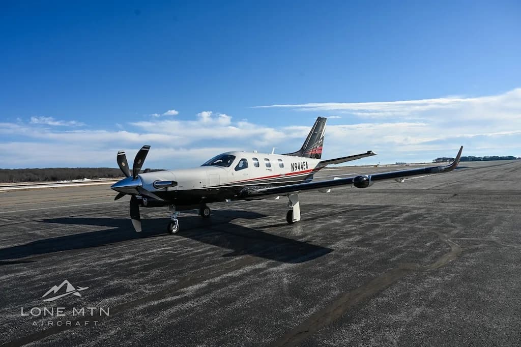 A TBM 940 aircraft, registration N944EA, parked on an asphalt runway or tarmac with a slight incline in the background.