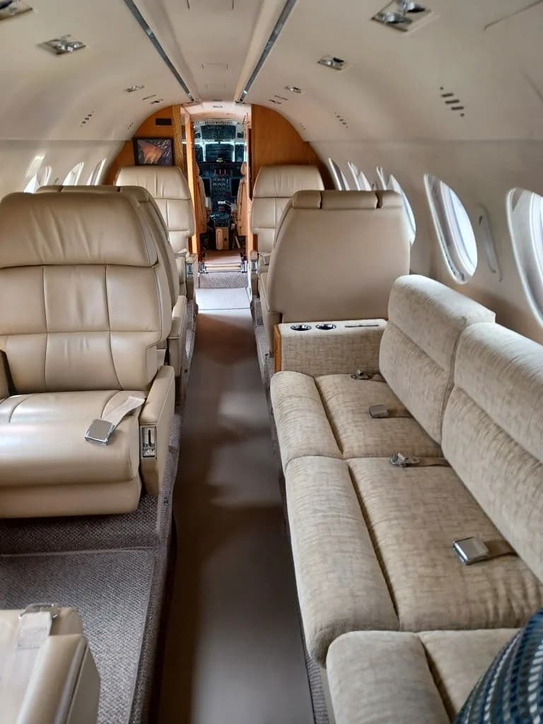 Aircraft cabin interior with beige leather seats and a couch.