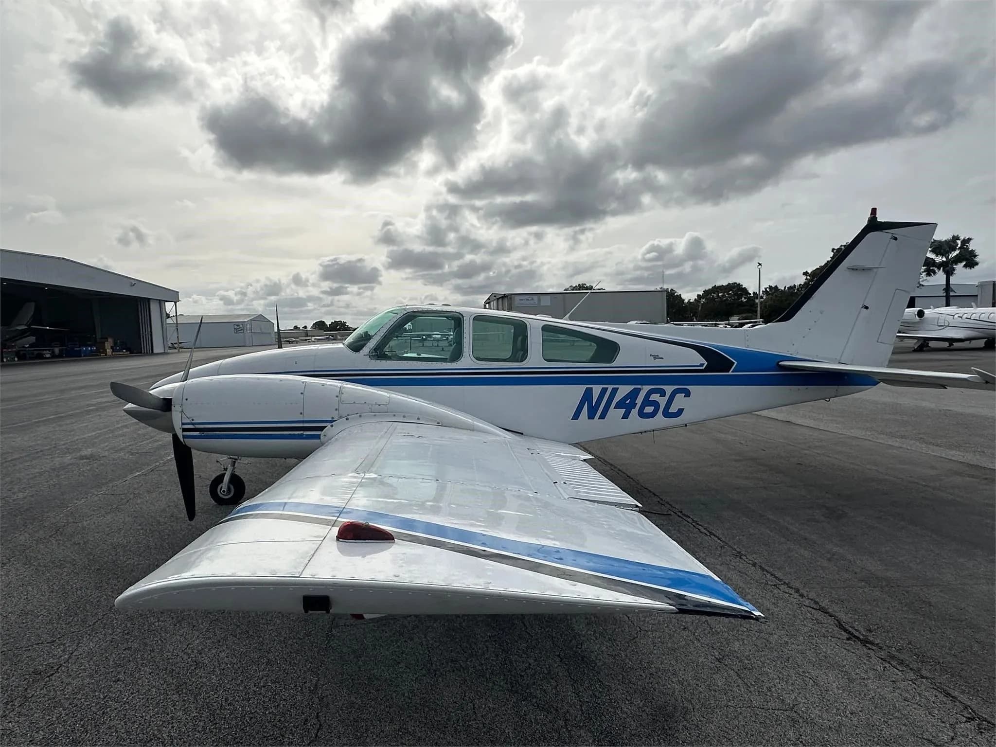 A side view of the white and blue twin-engine aircraft, N146C, parked on an airport tarmac.