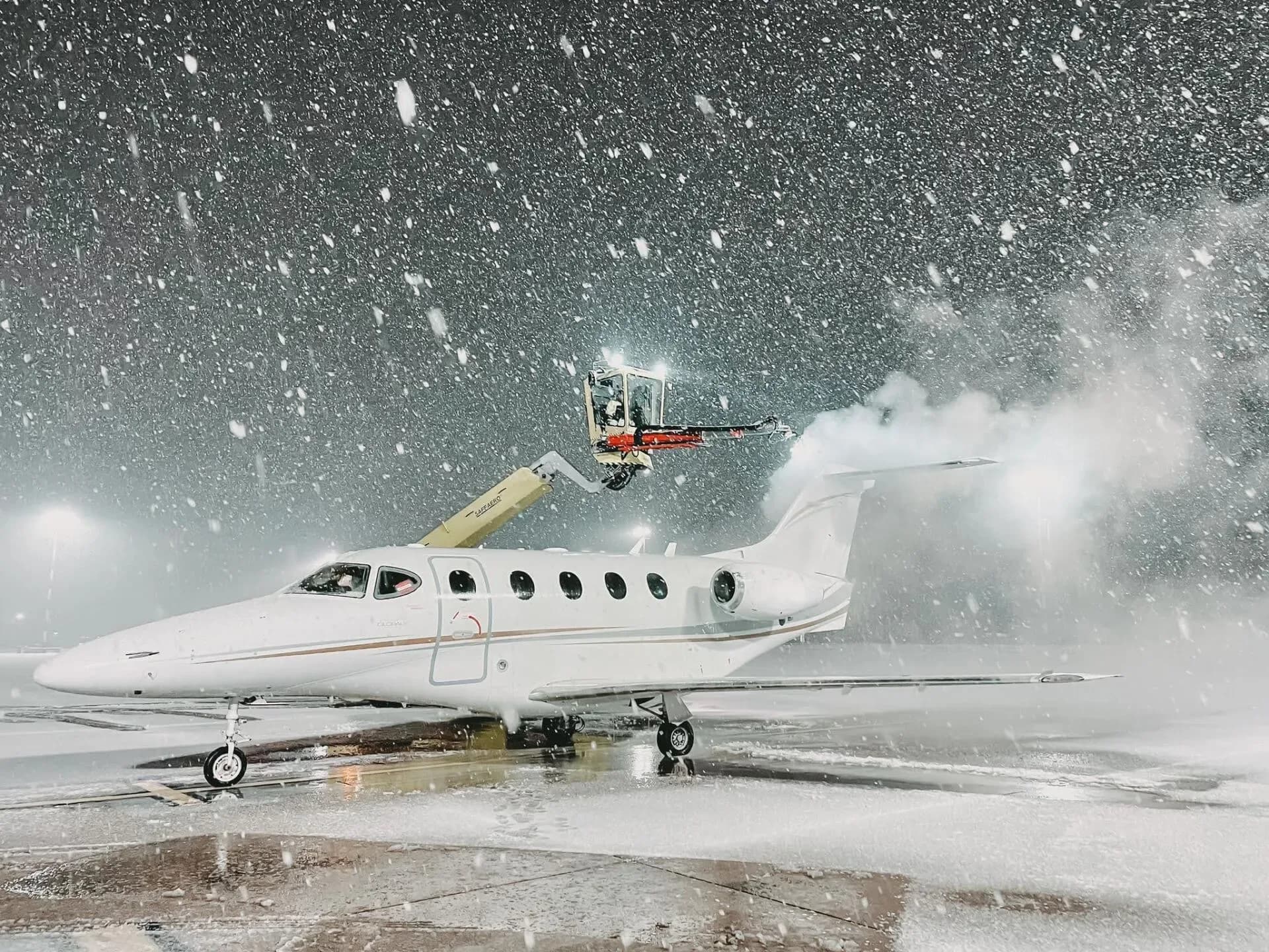 A white jet is de-iced in a snowstorm.