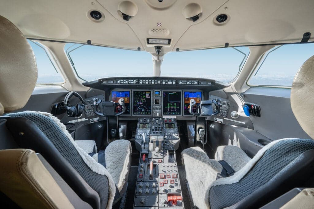 The cockpit of a Bombardier Challenger 350 aircraft features a full instrument panel and comfortable seating.