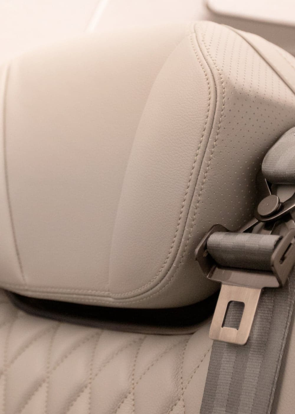 Close up of an aircraft seat headrest and seatbelt.