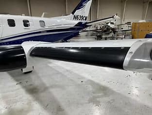 Close up of the wing of a white and blue aircraft in a hangar.