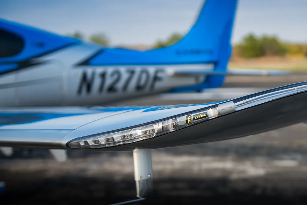 A close-up view of the wingtip and registration N127DF on the blue and silver Cirrus SR22T GTS Carbon aircraft.