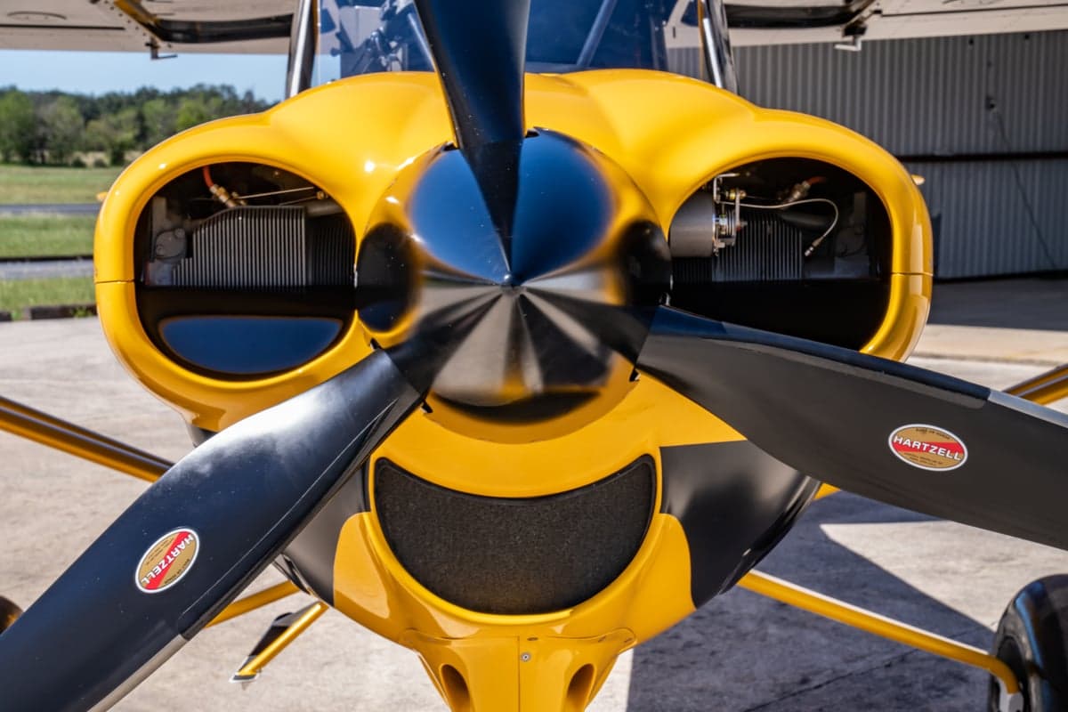 Close up of the propeller and engine of the yellow and black NX Cub aircraft.