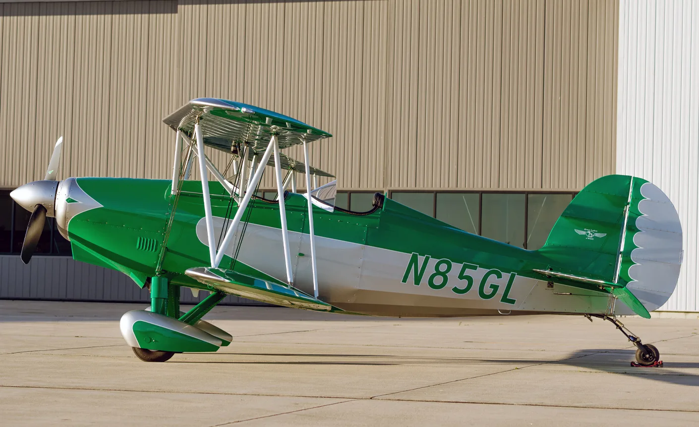 Side view of the N85GL biplane with green and silver paint scheme.