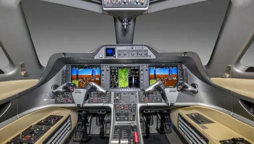 The cockpit of an Embraer Phenom 300 private jet, featuring a modern glass panel display with multiple screens.