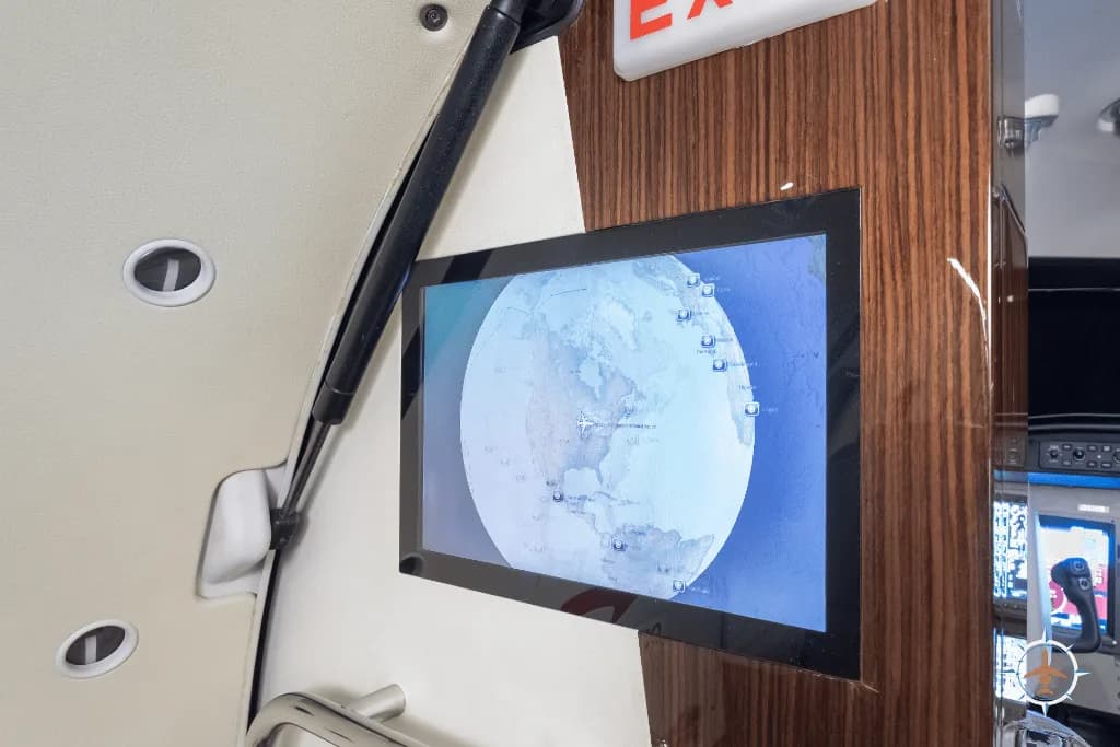 An in-flight entertainment screen displaying a global map, mounted on the aircraft's interior wall.