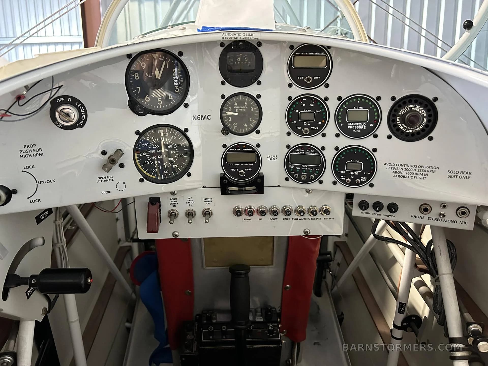 A white instrument panel with various gauges, switches, and a control stick visible in a small aircraft cockpit.