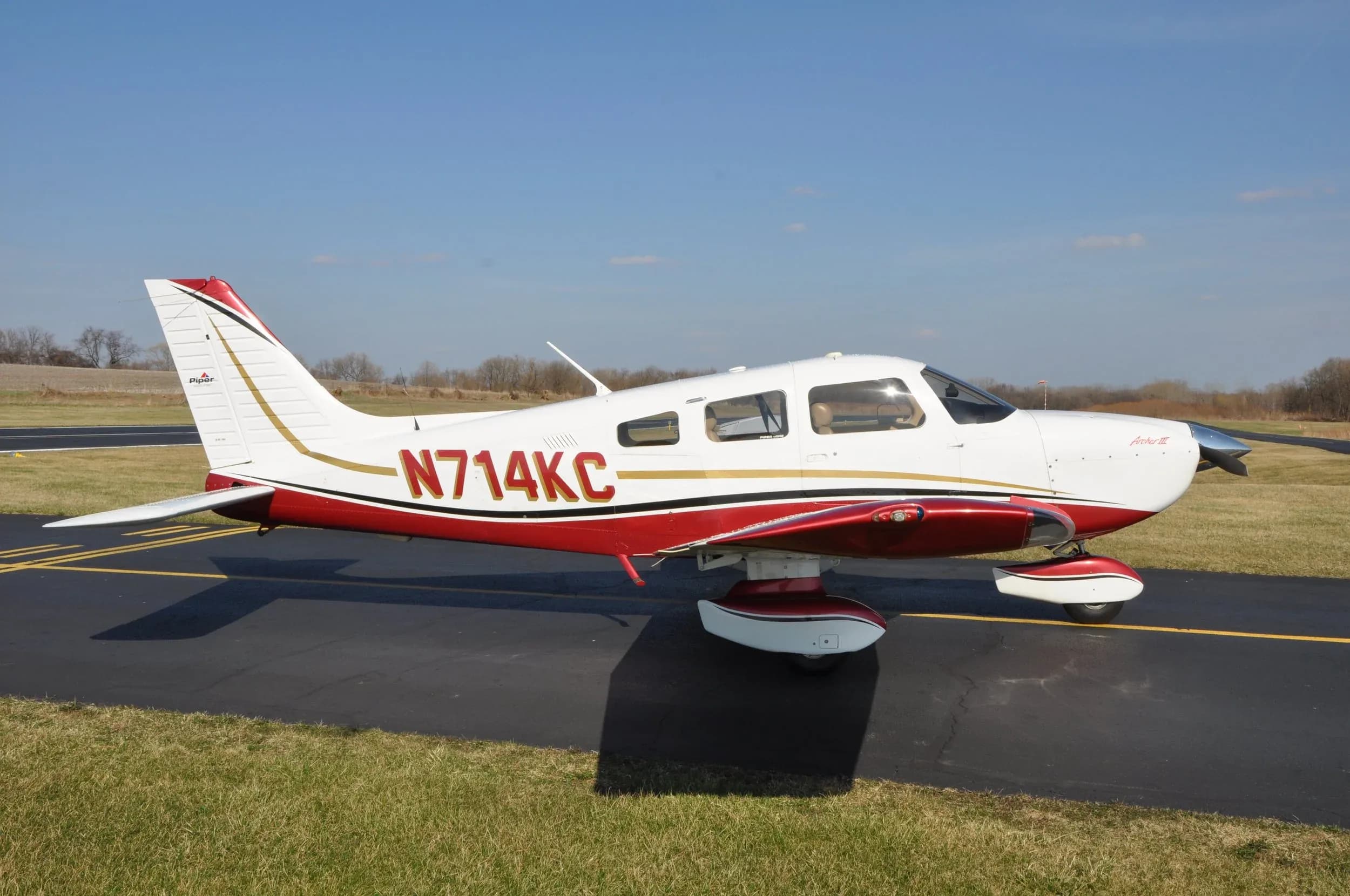 Piper Archer III aircraft with a white and red paint scheme on the tarmac.