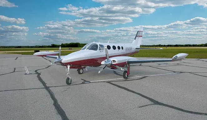 White and red twin engine aircraft parked on the tarmac.