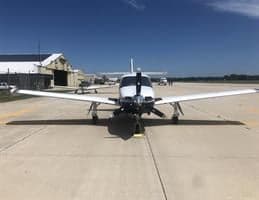 A white and blue aircraft is parked on the tarmac, facing the camera.