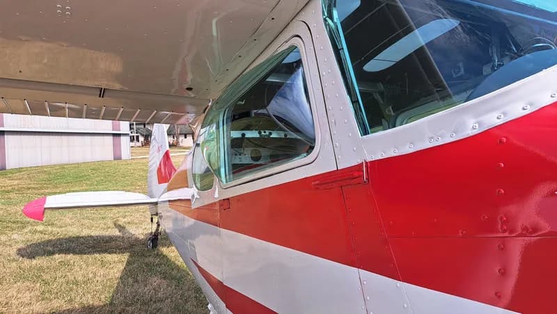 Close up of the side of a red and white Cessna, showing the cockpit window.